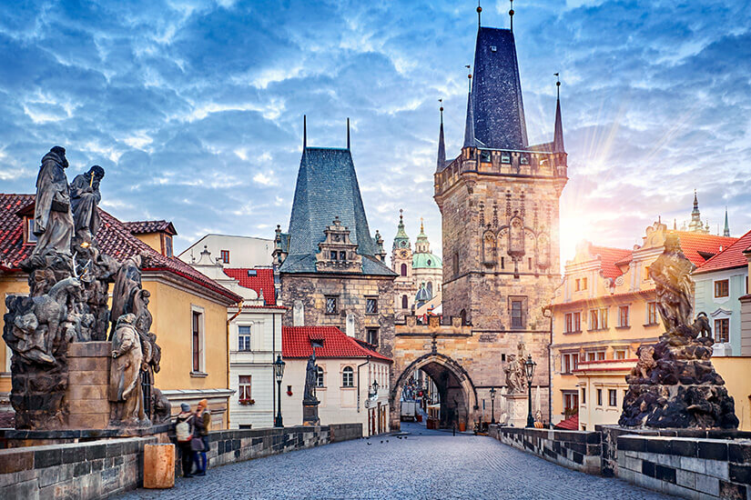Im warmen Morgenlicht erheben sich die markanten Türme der Kleinseitner Brückentürme am Ende der Karlsbrücke in Prag. Wochenendtrip Prag