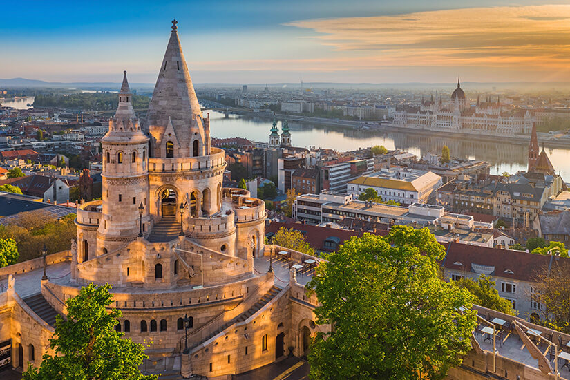 Im goldenen Licht des Sonnenaufgangs erhebt sich die märchenhafte Fischerbastei auf dem Burgberg von Budapest. Wochenendtrip Budapest