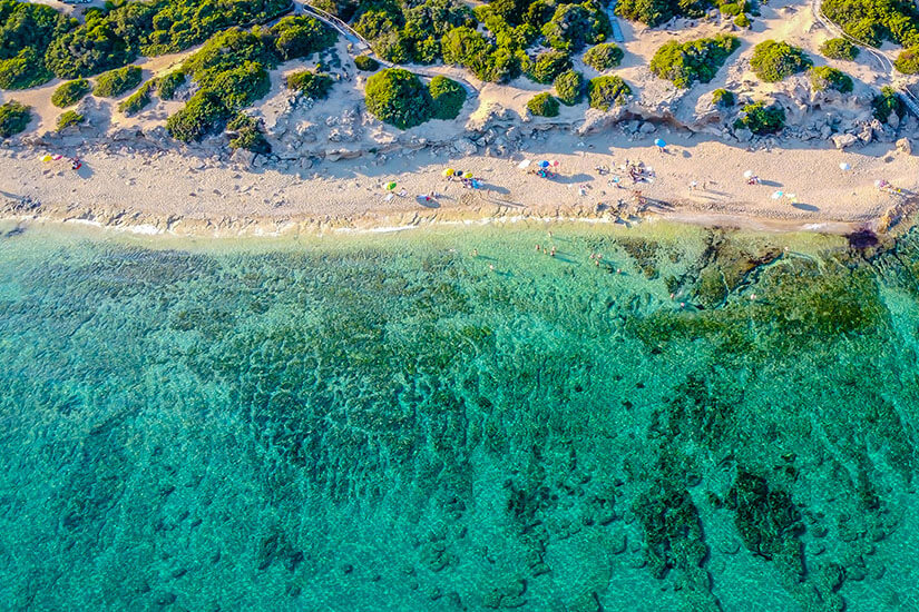 Luftaufnahme eines langen Sandstrands mit türkisfarbenem, glasklarem Meer. Die Szene erinnert an Karibik-Flair und lädt zum Baden und Entspannen ein Apulien oder Kalabrien Punta Prosciutto