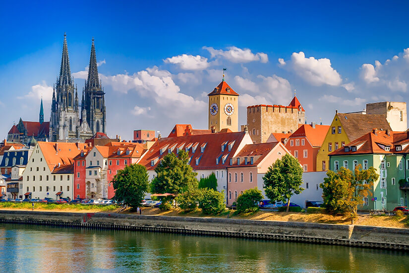 Blick über die Donau auf das Panorama der Regensburger Altstadt mit ihren bunten Häuserfassaden und roten Dächern am Flussufer. Schoenste Orte Sueddeutschland Regensburg