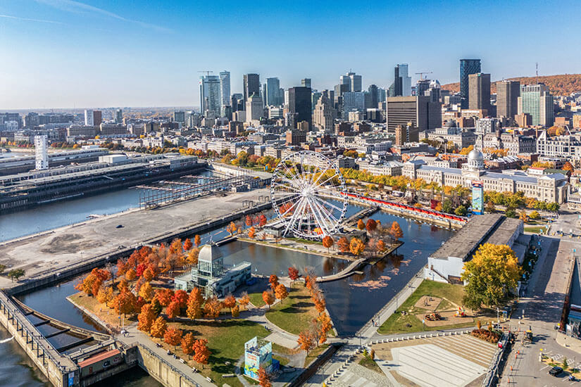 Hafenbereich einer Stadt mit Riesenrad und herbstlichen Bäumen. Im Hintergrund sind Wolkenkratzer zu sehen. Staedte Kanada Montreal
