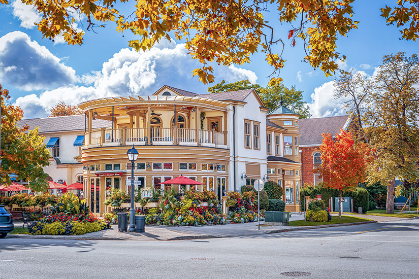Ein rundes, historisches Gebäude mit überdachter Veranda. Rundherum sind Bäume mit buntem Laub zu sehen. Kanada Niagara-on-the-Lake