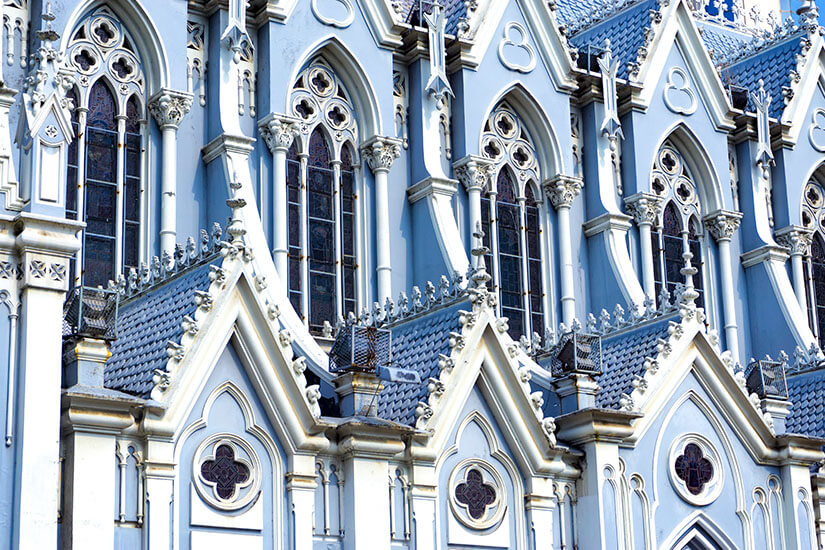 Die detailreiche Fassade einer hellblauen neugotischen Kirche zeigt spitze Bögen, verzierte Fenster und feine Ornamente. Die Architektur wirkt elegant und hebt sich durch ihre ungewöhnliche Farbe besonders hervor. Cali Kolumbien Kirche