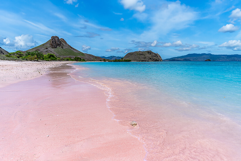 Der Pink Beach auf Komodo ist einer der wenigen rosafarbenen Strände weltweit – seine Farbe entsteht durch rote Korallenfragmente im weißen Sand. Das ruhige türkise Wasser und die kargen Hügel im Hintergrund verleihen der Szenerie etwas fast Unwirkliches. Der Strand liegt innerhalb des Komodo-Nationalparks und ist nur per Boot erreichbar. Indonesien Inseln Komodo