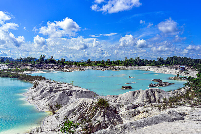 Der Kaolin-See auf Belitung entstand aus einem ehemaligen Zinnabbaugebiet und besticht durch sein milchig-türkisfarbenes Wasser inmitten weiß-grauer Lehmformationen. Die erodierten Uferböschungen bilden einen starken Kontrast zur Vegetation im Hintergrund. Natur und Bergbaugeschichte haben hier gemeinsam einen unerwarteten Schauplatz geschaffen. Indonesien Inseln Kaolin