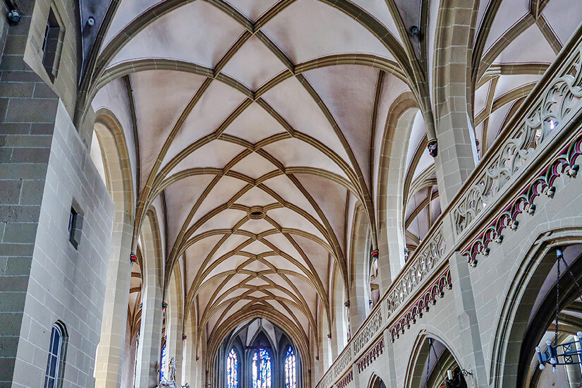 Das Gewölbe der Kirche St. Johannes ist zu sehen, eine harmonische Verbindung aus runden Holzbalken und hellem Stein. Kitzingen Unterfranken Kirche Innenraum
