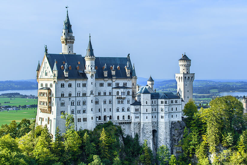 Das Schloss Neuschwanstein thront zwischen grünen Bäumen. Pfronten Allgaeu Neuschwanstein