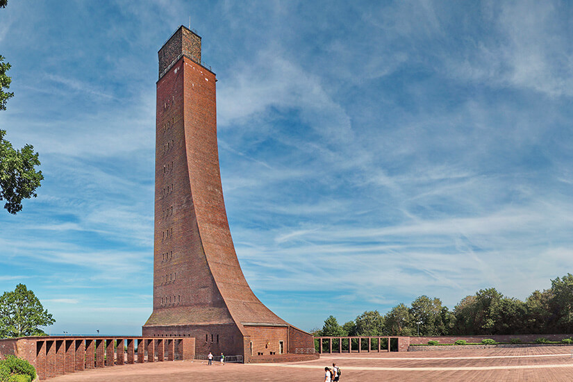 Das monumentale Marine-Ehrenmal erhebt sich mit seiner markanten Backsteinfassade vor einem weiten Platz. Der geschwungene Turm ragt eindrucksvoll in den blauen Himmel und bildet das unverwechselbare Wahrzeichen Laboës. Klare Linien und großzügige Flächen verleihen der Ansicht eine feierliche Wirkung. Hundestrände Ostsee Laboe