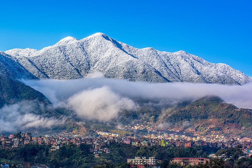 Eine Stadt in Nepal liegt vor dem verschneiten Gebirge des Himalayas. Nepal Willkommen