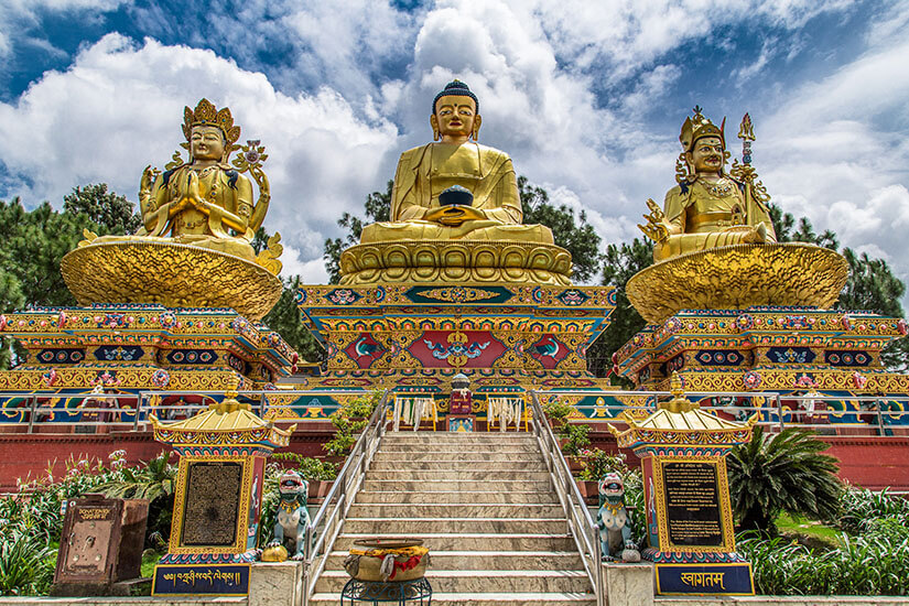 Drei große goldene Statuen thronen im Buddha Park von Kathmandu. Eine Treppe führt zu diesen gewaltigen Skulpturen hinauf. Nepal Kathmandu Buddha Park