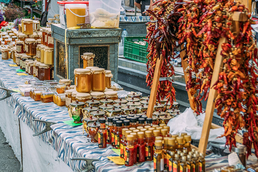 Selbe Prozedur, bitte. Kunstvoll aufgetürmt präsentieren sich auf einem Marktstand zahlreiche Honiggläser mit Stoffdeckeln, kleine Fläschchen und Chutneys, während daneben lange Bündel getrockneter roter Paprika baumeln. Mallorca Souvenirs Honig