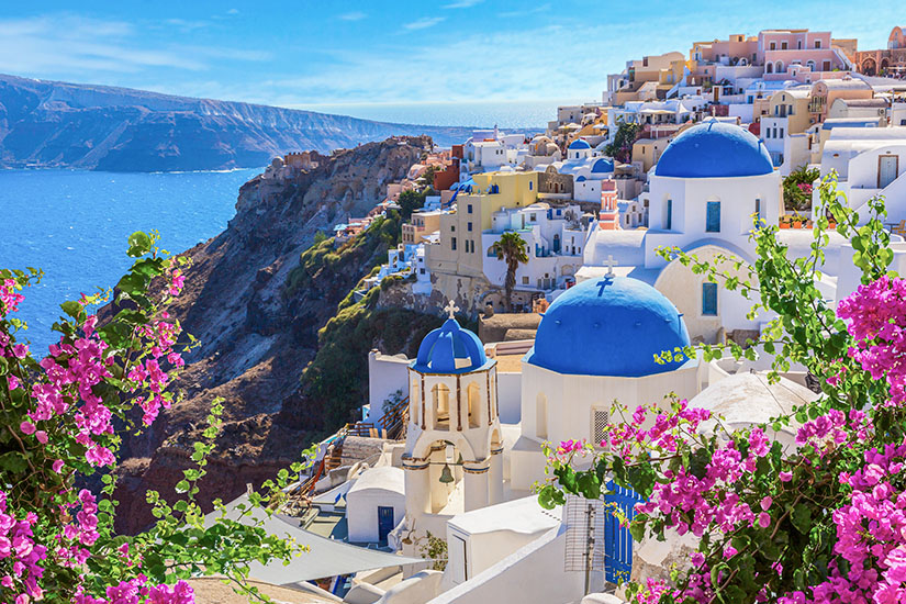 Weiße Häuser und tiefblaue Kirchenkuppeln schmiegen sich auf Santorini an den steilen Rand der Caldera. Pinkfarbene Bougainvilleen setzen leuchtende Akzente und machen verständlich, warum das Eiland oft als schönste griechische Insel bezeichnet wird. Griechsiche Inseln Santorini