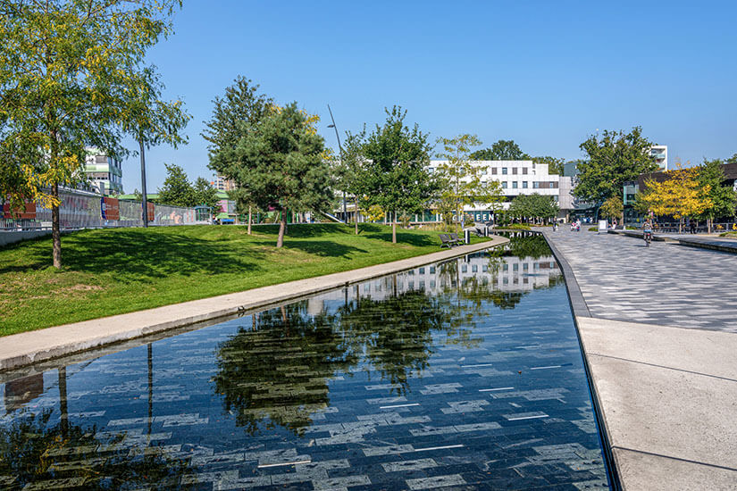 Der modern gestaltete Raadhuisplein im Zentrum von Emmen mit Wasserbecken, Grünflächen und zeitgenössischer Architektur. Die fußgängerfreundliche Altstadt präsentiert sich hier von ihrer frischesten Seite. Dieser Platz verbindet Einkaufsmeile, Kulturbauten und Erholungsflächen auf engstem Raum. Emmen Niederlande Raadhuisplein