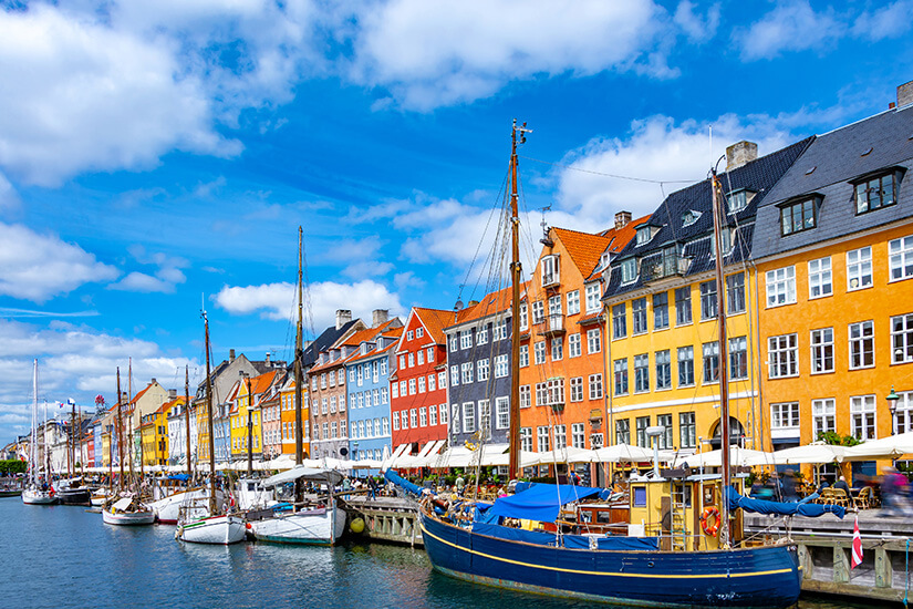Die bunte Häuserfassade vom Stadtviertel Nyhavn in Kopenhagen ist zu sehen. Im Wasser ankern kleine Boote. Kopenhagen Sehenswuerdigkeiten Nyhavn