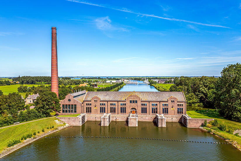 Das mächtige Lemmer Pumpwerk mit seiner roten Fassade am Wasser ist zu sehen. Lemmer Niederlande Woudagemaal