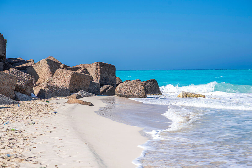 Puderweißer Sandstrand trifft auf leuchtend türkise Wellen an der ägyptischen Nordküste. Große Felsbrocken rahmen den Küstenstreifen ein und verleihen der Szenerie einen wildromantischen Charakter. Der Sahel gehört zu den beliebtesten Badeorten in Ägypten für einheimische Sonnenanbeter. Ägypten Strände Sahel