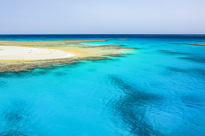 Puderweiße Sandbank umgeben von leuchtendem Türkis – die Hamata Islands im südlichen Roten Meer. Das Qulaan-Archipel trägt den Beinamen „ägyptische Malediven" und gilt als eines der bestgehüteten Geheimnisse des Landes. Die Farbenpracht des Wassers wirkt aus der Vogelperspektive fast unwirklich. Ägypten Strände Hamata Islands