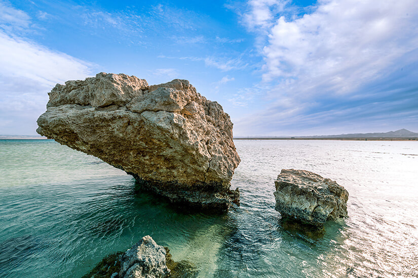 Eine markante Felsformation ragt aus dem glasklaren, smaragdgrünen Wasser bei Sharm El Luli im tiefen Süden des Roten Meeres. Die einsame Küste wirkt völlig unberührt und gehört zu den ruhigsten Stränden des gesamten Landes. Ägypten Strände Sharm El Luli Beach