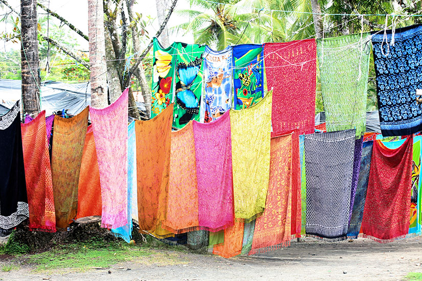 Zu erkennen sind zahlreiche farbenfrohe Tücher und Stoffe, die an Leinen aufgehängt sind. Sie weisen unterschiedliche Muster und kräftige Farben wie Rot, Pink, Gelb, Grün und Blau auf. Costa Rica Mitbringsel Tuecher