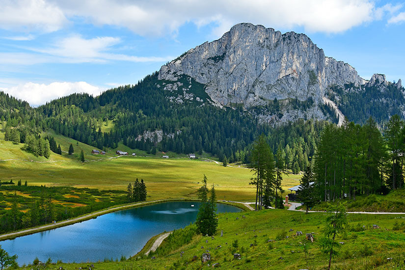Ein Berg erhebt sich über grüner Landschaft, durch die ein Fluss führt. Steyr Oesterreich Kalkalpen