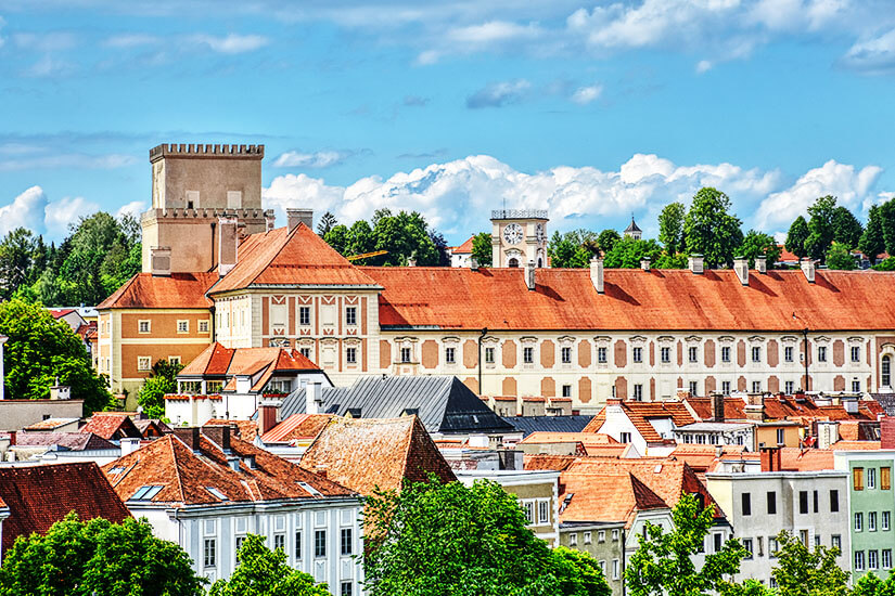 Schloss Lamberg thront über der Stadt Steyr. Das Gebäude ist von Türmen sowie verzierten weißen Hausfassaden und roten Dächern geprägt. Steyr Oesterreich Schloss
