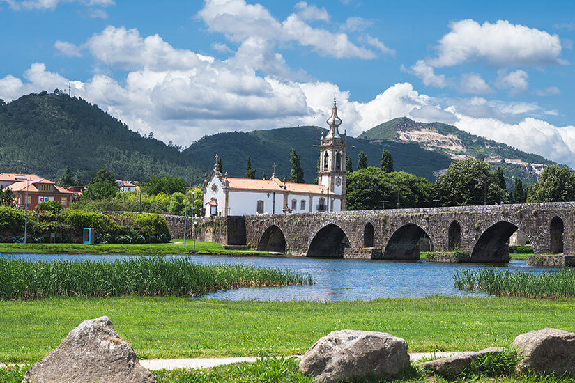 Über den ruhigen Rio Lima zieht sich die jahrhundertealte Steinbrücke von Ponte de Lima mit ihren zahlreichen Bögen, an deren Ende die weiß getünchte Kirche Santo António da Torre Velha mit ihrem verzierten Glockenturm steht. Top Tagestrips Porto Ponte de Lima