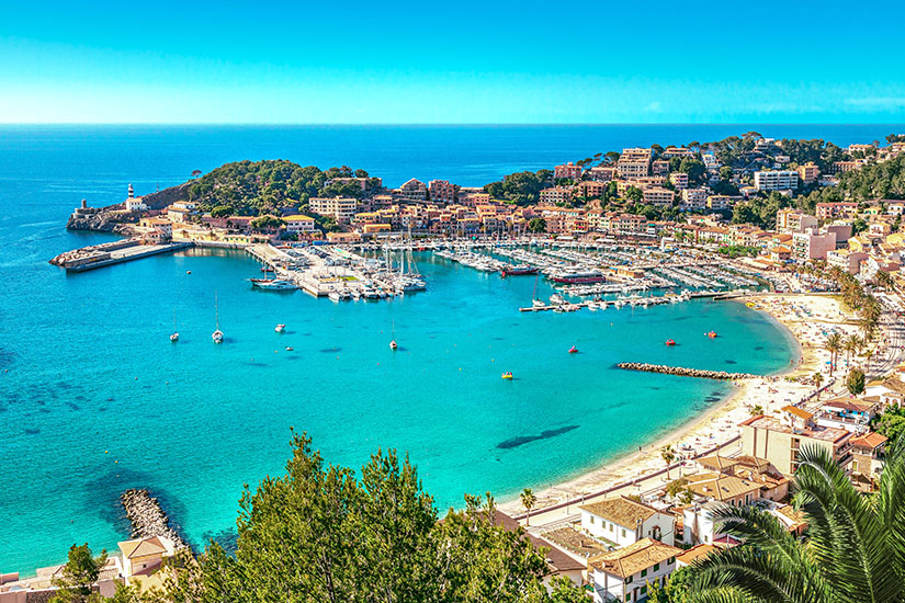 Port Soller auf Mallorca ist zu sehen. Türkisblaues Meer liegt vor dem Ort mit hellen Häusern und Sandstränden. All Inclusive unter 1000 Euro Mallorca