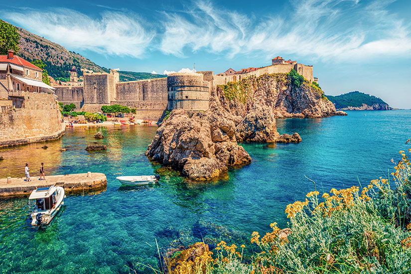 Mächtige Stadtmauern und die runde Festung Bokar thronen auf schroffen Felsen über der kleinen Bucht vor Dubrovniks Altstadt, die in Game of Thrones als Kulisse für Königsmund diente. Game of Thrones Drehorte Dubrovnik