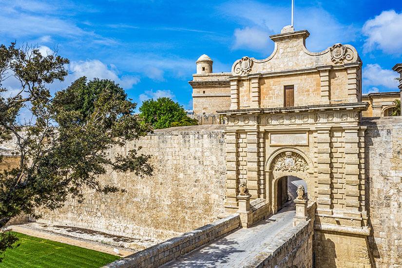 Über eine steinerne Brücke führt der Weg zum prachtvollen barocken Haupttor von Mdina, das mit Wappen, Reliefs und Löwenfiguren verziert in die mächtige, honigfarbene Stadtmauer eingelassen ist. Game of Thrones Drehorte Malta