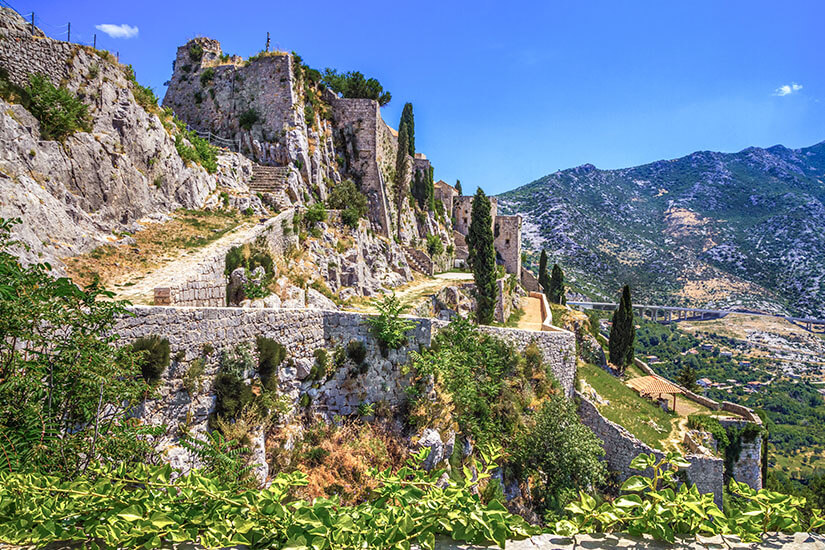 Auf einem schroffen Kalksteinfelsen oberhalb von Split erhebt sich die mittelalterliche Festung Klis, deren verwinkelte Mauern, Treppen und Türme sich den Hang hinaufziehen. Game of Thrones Drehorte Split