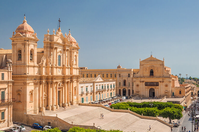 Die Kathedrale von Noto aus hellem Stein ist zu sehen. Eine imposante Treppe führt zu ihr hinauf. White Lotus Drehorte Noto